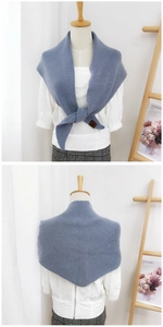 Detail of blue knitted shawl featuring fine ribbed texture and a brown leather logo tag