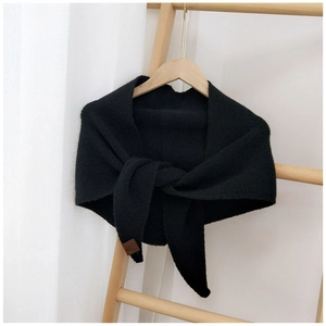Detail of black knitted triangle scarf with brown leather tag and soft ribbed texture