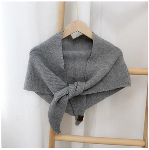 Detail of grey knitted triangular scarf with ribbed texture and brown leather label