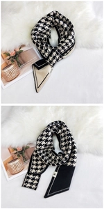 Close-up of black and white houndstooth knit scarf with brand label on a soft rug