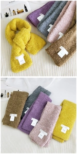 Detail of colorful bouclé scarves showing thick curly plush texture and textile labels