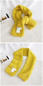 Detail of ginger yellow curly plush scarf featuring a soft texture and woven label
