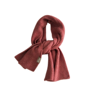 Sciarpa invernale in maglia spessa color rosso mattone con trama a coste ed etichetta