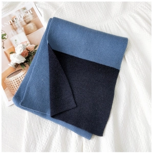 Dettaglio della trama in maglia di una sciarpa bicolore blu su sfondo bianco testurizzato