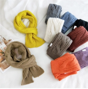 Flat lay detail of various colorful cable knit scarves in thick soft wool texture