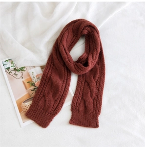 Close-up of dark red cable knit wool scarf texture on a soft white fabric background