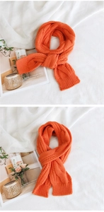 Detailed view of bright orange knitted scarf with classic thick cable knit texture and pattern