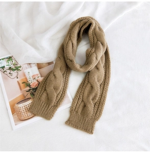 Detail view of the thick cable knit texture on a khaki winter scarf for women