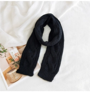 Close-up of black cable knit scarf with thick wool texture on white fabric background