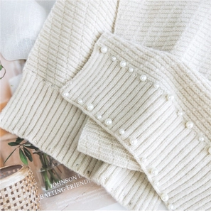 Detailed close-up of soft beige knit sleeve cuff with elegant pearl bead embellishments