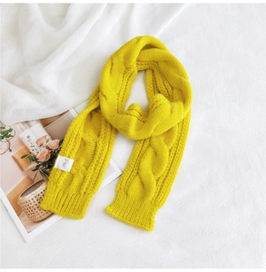 Detailed macro shot of yellow chunky knit scarf featuring classic cable patterns