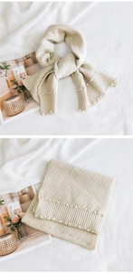 Detail view of beige knitted scarf with pearl accents and thick ribbed texture design