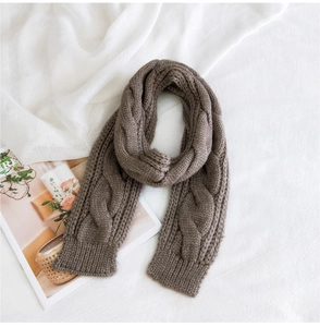 Detail of soft brown cable knit scarf with thick ribbed edges on white background