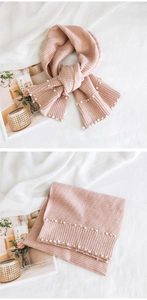 Pink knitted scarf detail with soft ribbed texture and elegant pearl accents on the ends