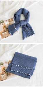 Detail of navy knit scarf featuring elegant pearl embellishments and ribbed texture edges