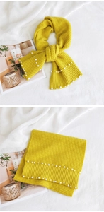 Detail of yellow knitted scarf with ribbed edges and elegant white pearl embellishments