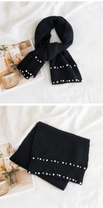 Close-up of black knit scarf with elegant double-row pearl beads and soft texture