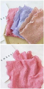 Détail de foulards plissés en coton et lin aux tons pastel rose, violet et orange