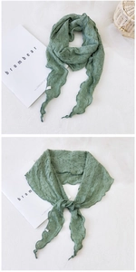 Détail d'une écharpe plissée vert clair avec texture gaufrée et finition ourlet ondulé