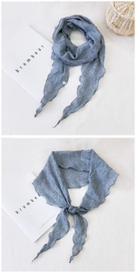 Détail d'une écharpe bleu gris en coton avec texture plissée et bords ondulés