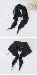 Détail du foulard plissé noir avec bordure blanche et texture de tissu gaufré