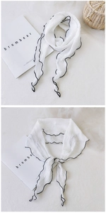 Détail d'un foulard en coton lin plissé blanc avec finition de bord ondulé noir
