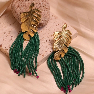 Detail of golden monstera leaf alloy earrings with long green bead fringe tassels