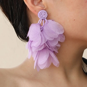 Detail of purple handmade tiered fabric petal tassel earrings on a model’s side profile