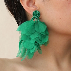 Detailed close-up of emerald green layered mesh petal earrings on female model
