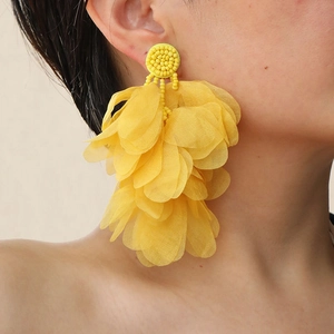 Detailed view of yellow handmade fabric petal earrings with bohemian tassel design