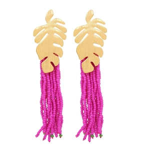 Detail of gold tropical monstera leaf earrings with vibrant pink beaded tassel fringe