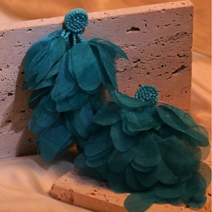 Macro shot of large dark teal handmade fabric petal tassel earrings on a stone display