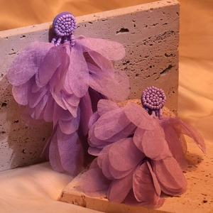 Macro detail of purple handmade fabric petal earrings with intricate beadwork texture