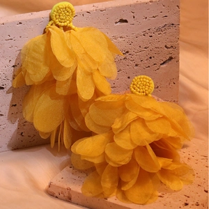 Detailed close-up of handmade yellow layered fabric flower earrings with beaded studs