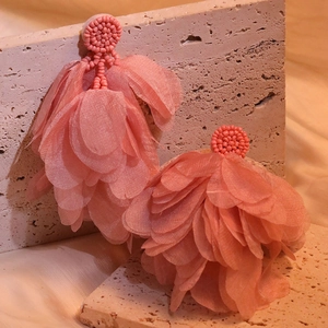 Detail of pink petal tassel earrings with hand-sewn beads on textured stone base