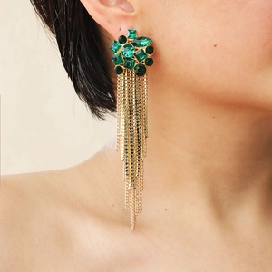 Macro shot of long gold tassel earrings with emerald green multi-shape gemstones