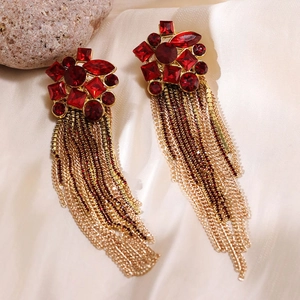Close-up of elegant long tassel earrings with red crystals and gold metal chains