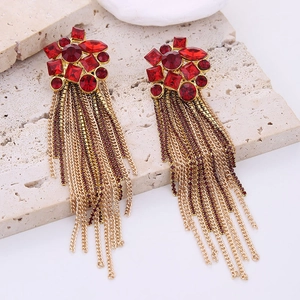 Macro shot of long gold tassel earrings with red rhinestones and crystal studs