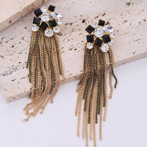 Close-up of long tassel earrings featuring gold chains with black and clear crystals