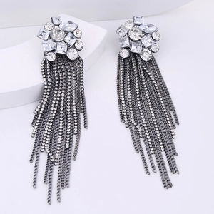 Macro detail of long silver tassel earrings with sparkling rhinestones on white display