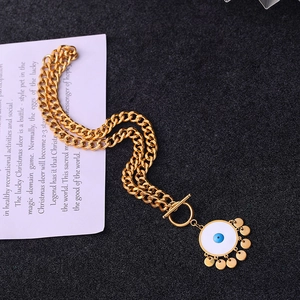 Detail of gold Cuban chain necklace with evil eye pendant and toggle clasp closure