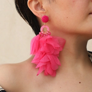 Detailansicht großer pinkfarbener Stoffblumen-Ohrringe, getragen von einem Modell