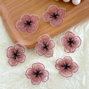 Vue détaillée d'appliques fleurs brodées à quatre feuilles roses sur plateau bois pour DIY
