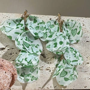 Détail de boucles d'oreilles pendantes en tissu à motif cœur vert sur pierre