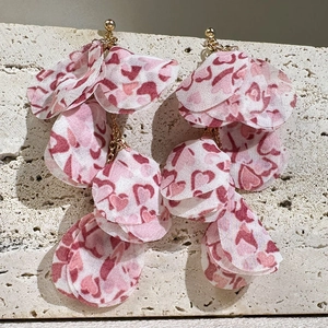 Détail macro de pétales de tissu à cœurs superposés sur de longues boucles d'oreilles