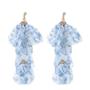 Gros plan de boucles d'oreilles à pompons avec pétales en tissu bleu et motifs de cœur