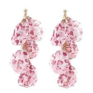 Détail de boucles d'oreilles longues à glands fleuris avec motifs de cœurs roses