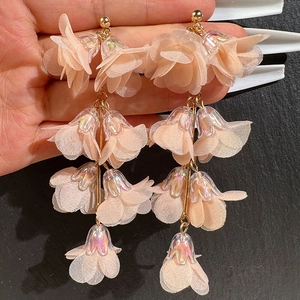 Detail of pink fabric flower earrings with long layered tassels and golden metal chain