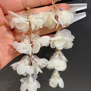 Detail of layered white fabric flower tassel earrings with iridescent pearl base