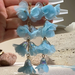 Detail of blue mesh flower tassel earrings with golden metal beads and long pendant drop